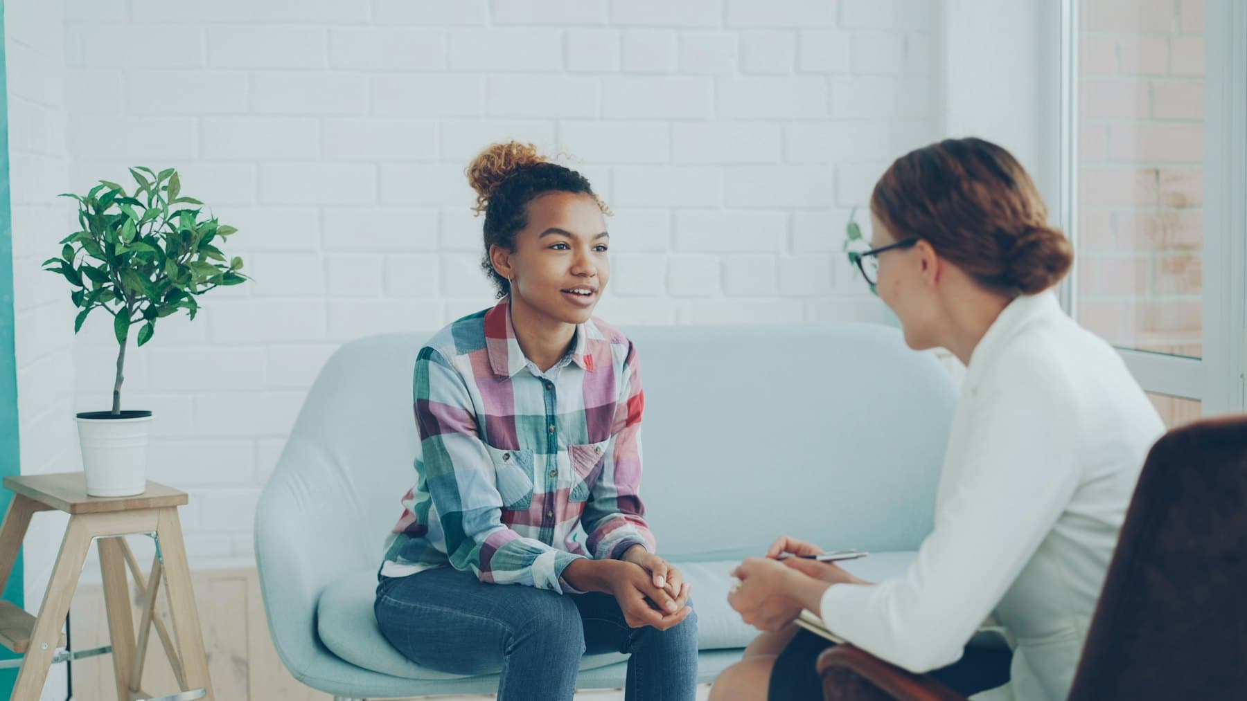 A recovery coach and a participant talking together in a bright, relaxed room