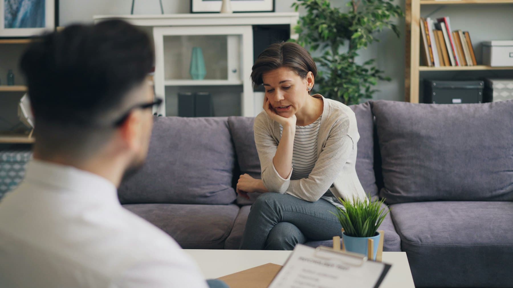 A support coordinator reviewing paperwork with two participants on a sofa